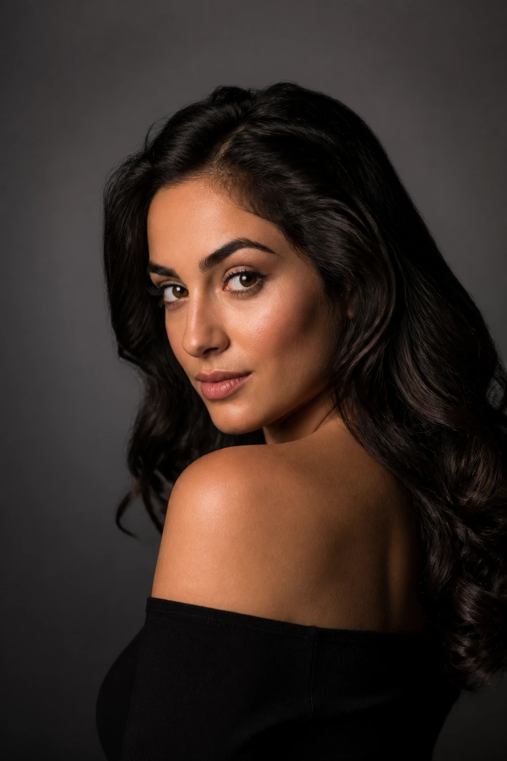 Woman in a black off-shoulder top looking over her shoulder, soft key from camera-left with a lit triangle on the far cheek against charcoal.